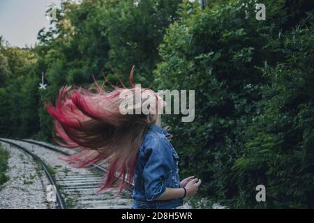 Flying long hair blonde girl in nature. The hair is blonde with pink dyed tips. Stock Photo