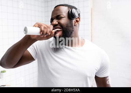 afro-american man with headphones singing in toothbrush Stock Photo