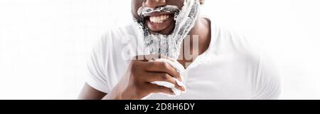 panoramic view of smiling afro-american man with shaving foam on face looking at camera Stock Photo