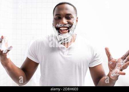 laughing afro-american man with shaving foam on face looking at camera Stock Photo