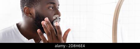 panoramic shot of afro-american man applying cure for strengthening beard growth Stock Photo