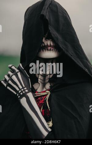 Portrait of young woman in Halloween costume of death with painted skeleton on her body and sugar skull makeup. Halloween concept. Stock Photo