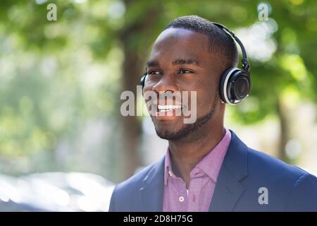 African American Man Listening Music On Wireless Headphones Outside Stock Photo
