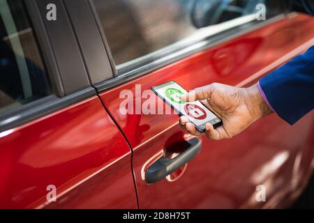 African Man Unlocking Car Using Smartphone App Stock Photo