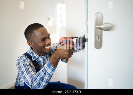 African Locksmith Man Changing And Fixing Door Lock Stock Photo