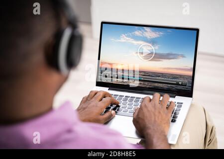 Young African Man Watching Video On Laptop Stock Photo