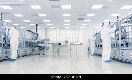 Team of Research Scientists in Sterile Suits Working with Computers, Microscopes and Modern Industrial Machinery in the Laboratory. Product Stock Photo