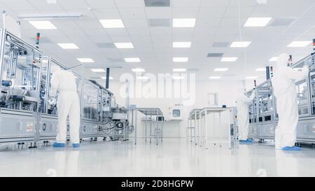Team of Research Scientists in Sterile Suits Working with Computers, Microscopes and Modern Industrial Machinery in the Laboratory. Product Stock Photo
