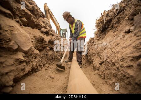 A construction worker works to install a new water line underground on the island of Santiago, Cabo Verde. Stock Photo