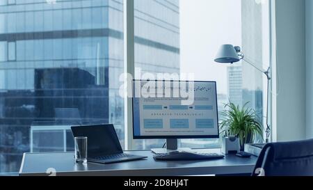 Shot of the Office Desk with Personal Computer Standing on It. Future Computing Plans Shown on Monitor. Modern Stylish Room with a Big City Business Stock Photo