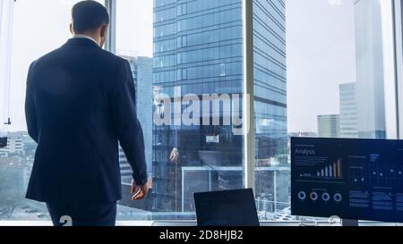 Shot of the Confident Businessman in a Suit Walking Through His Office and Looking out of the Window Thoughtfully. Stylish Modern Business Office with Stock Photo