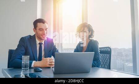 Female Top Manager and Male Businessman Sitting at the Desk Having Discussion and Working on the Laptop. Trying to Find Successful Solution to the Stock Photo