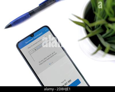 Lod, Israel - July 8, 2020: Modern minimalist office workspace with black mobile smartphone with TeamViewer QuickSupport app launch screen with logo Stock Photo