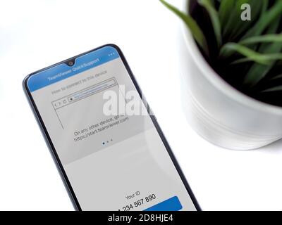 Lod, Israel - July 8, 2020: Modern minimalist office workspace with black mobile smartphone with TeamViewer QuickSupport app launch screen with logo Stock Photo