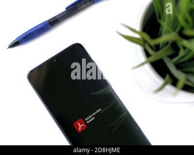 Lod, Israel - July 8, 2020: Modern minimalist office workspace with black mobile smartphone with Adobe Acrobat Reader app launch screen with logo on w Stock Photo