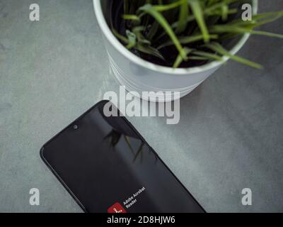 Lod, Israel - July 8, 2020: Modern minimalist office workspace with black mobile smartphone with Adobe Acrobat Reader app launch screen with logo on m Stock Photo