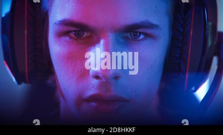 Portrait of the Young Handsome Pro Gamer Playing in Online Video Game. Neon Colored Room. e-Sport Cyber Games Internet Championship. Stock Photo