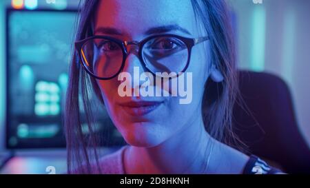 Portrait of the Beautiful Young Pro Gamer Girl Sitting at Her Personal Computer and Looks into Camera. Attractive Geek Girl Player Wearing Glasses in Stock Photo