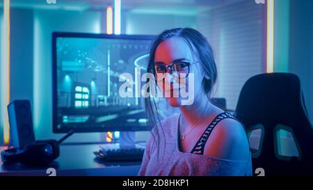 Portrait of the Beautiful Young Pro Gamer Girl Sitting at Her Personal Computer and Looks into Camera. Attractive Geek Girl Player Wearing Glasses in Stock Photo