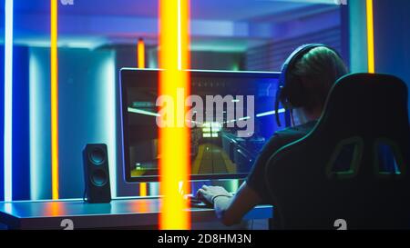 Pro Gamer Plays in the First Person Shooter on His Personal Computer. Talks with Teammates through Headphones. Neon Colored Room. Online eSport Stock Photo