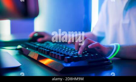 Close-up on the Hands of the Gamer Playing in the Video Game on a Keyboard and Using Mouse. Stylish Arcade Neon Bright Red, Pink, Violet, Green Colors Stock Photo