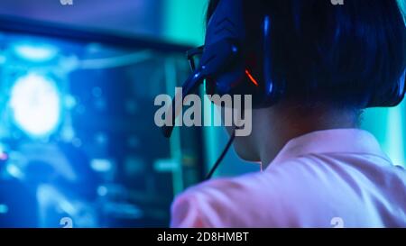 Close-up Portrait Shot of the Professional East Asian Gamer Playing in Online Video Game on His Personal Computer. Talking into Microphone. Room Lit Stock Photo