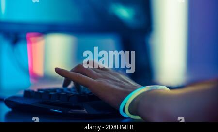 Close-up on the Hands Typing Playing on Keyboard. Stylish Arcade Neon Bright Red, Pink, Violet, Green Colors. Stock Photo