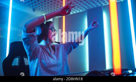 Low Angle Shot of the Beautiful Friendly Pro Gamer Girl Streaming Online Video Game and Winning it, Wearing Headset and Shares with Her Fans Stock Photo