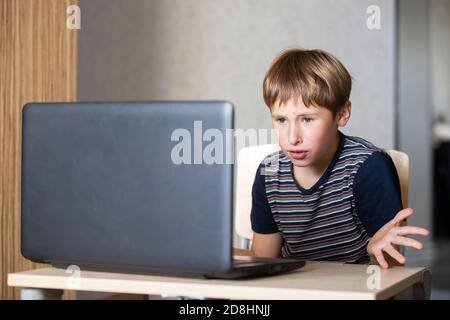 Schoolboy during online lesson at home, social distance during quarantine, self-isolation, online education concept. Elementary age boy at laptop at h Stock Photo
