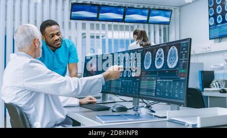 Medical Scientist and Surgeon Discussing CT MRI Brain Scan Images on a Personal Computer in Laboratory. Neurologists Neuroscientists in Neurological Stock Photo