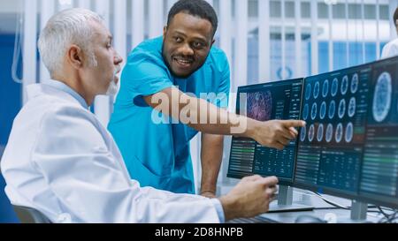 Medical Scientist and Surgeon Discussing CT MRI Brain Scan Images on a Personal Computer in Laboratory. Neurologists Neuroscientists in Neurological Stock Photo