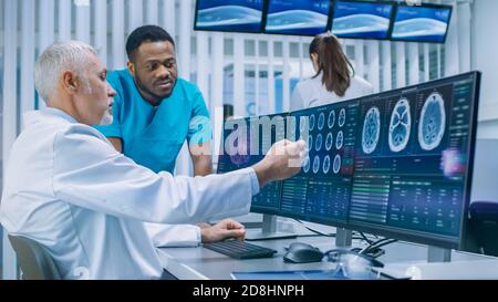 Medical Scientist and Surgeon Discussing CT MRI Brain Scan Images on a Personal Computer in Laboratory. Neurologists Neuroscientists in Neurological Stock Photo