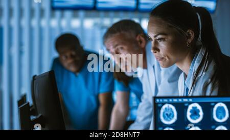 Diverse Group of Medical Scientists Solve Problems and Point at Computer Screens Showing CT, MRI Scans. Neurologists Neuroscientists Working in Brain Stock Photo