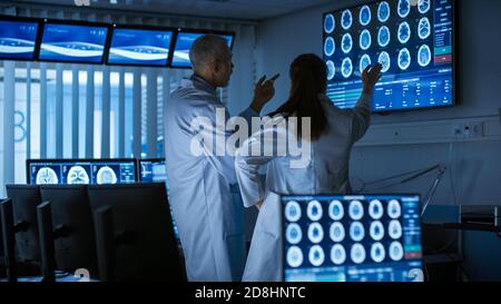 Two Medical Scientists Neurologists, Talking and Working on a Personal Computer in Modern Laboratory. Research Scientists Making New Discoveries in Stock Photo