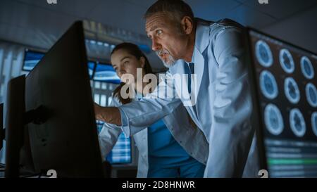 Two Medical Scientists Neurologists, Talking and Working on a Personal Computer in Modern Laboratory. Research Scientists Making New Discoveries in Stock Photo