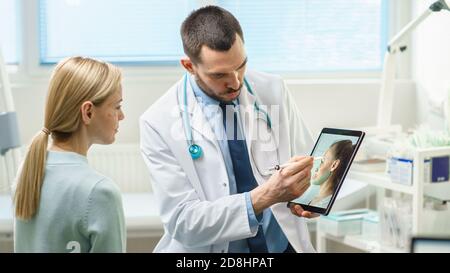 Plastic Cosmetic Surgeon Consults Woman about Facial Lift Surgery, He Draws Arrows on Digital Tablet Computer Screen, Showing Types of Facelift and Stock Photo