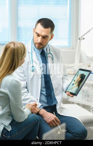 Plastic Cosmetic Surgeon Consults Woman about Facial Lift Surgery, He Draws Arrows on Digital Tablet Computer Screen, Showing Types of Facelift, Cheek Stock Photo
