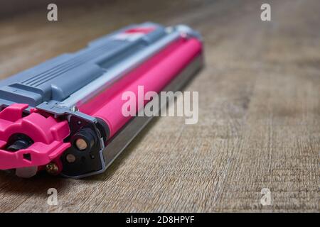 Magenta toner cartridge for a laser printer on wooden table Stock Photo