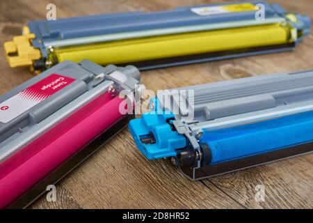 Three toner cartridges for color laser printer stacked on wooden table Stock Photo