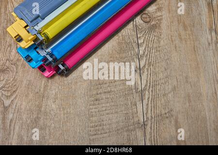 Three toner cartridges for color laser printer stacked on wooden table Stock Photo