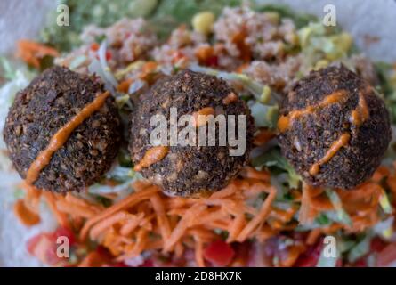 Fried falafal balls with colourful salad in a wrap, with sauce over. Stock Photo