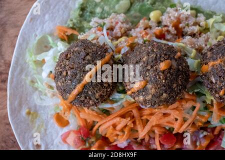 Fried falafal balls with colourful salad in a wrap, with sauce over. Stock Photo