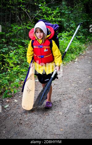 Small traveler carries gear on portage while Canoeing in Ontario's Algonquin ProvinciaL PARK, ONTARIO, CANADA. Stock Photo