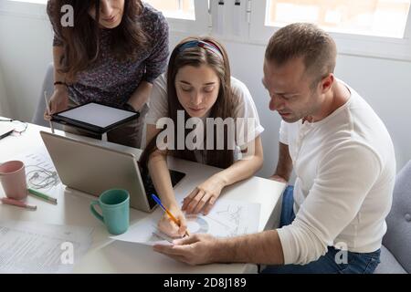 High angle of serious man and women analyzing graphs on document in office together Stock Photo