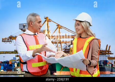 Female industrial engineer wearing a white helmet while standing in a construction site with businessman talking on working plan, Engineer and archite Stock Photo