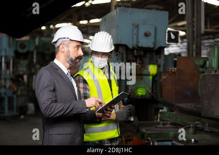 Male Industrial Engineers Talk with Factory Worker . They Work at the Heavy Industry Manufacturing Facility. Stock Photo