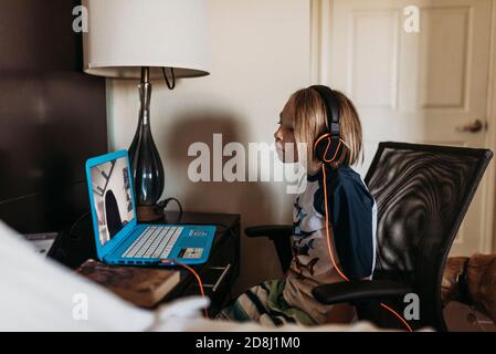 School age boy distance learning in hotel room during pandemic Stock Photo