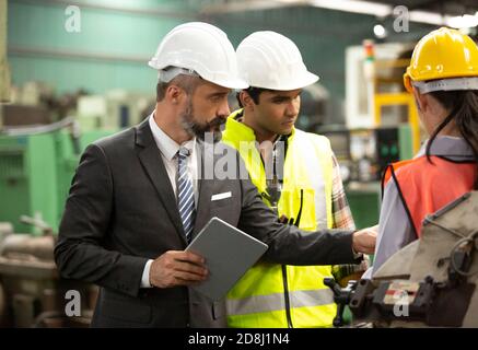 Male Industrial Engineers Talk with Factory Worker . They Work at the Heavy Industry Manufacturing Facility. Stock Photo