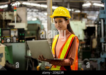 Female technician worker in uniform working on laptop with machine in manufacturing. Stock Photo