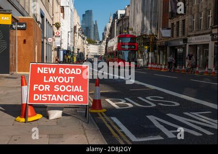 LONDON - SEPTEMBER 13, 2020: Social Distancing new road layout sign with London Double Decker Bus and St Paul's Cathedral in the background during Cov Stock Photo